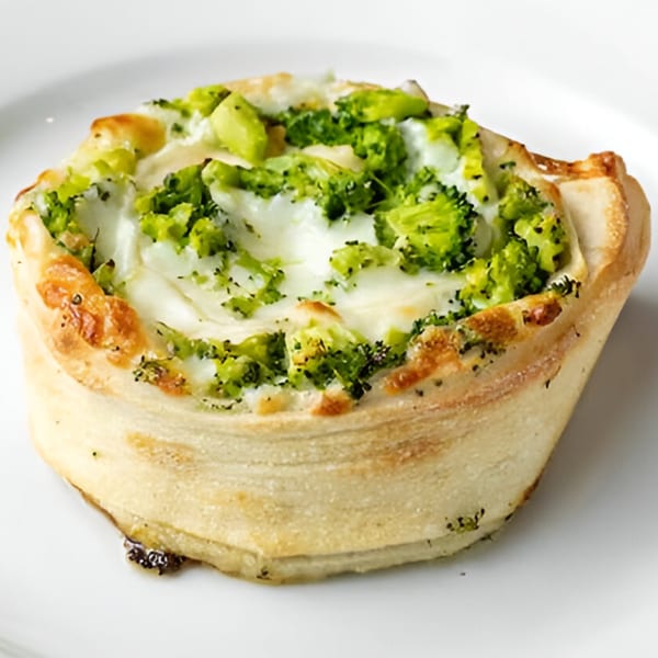 A round, individual broccoli and cheese pizza cup from Phil's Pizzeria on a white plate.