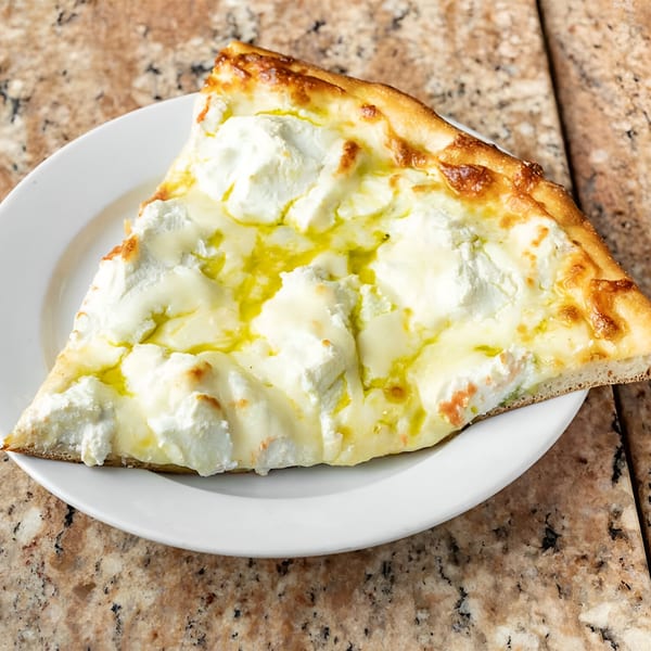 A slice of white pizza from Phil's Pizzeria, topped with ricotta cheese and olive oil.